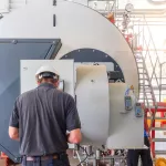 Maintenance engineer working with gas boiler of heating system equipment in a boiler room