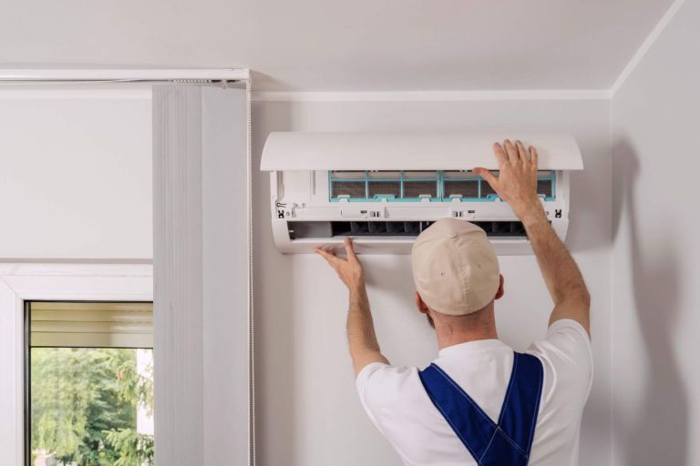 Technician maintenance air conditioning open ac unit to checking filters in a living space. Service includes cleaning, replacement elements, ensuring optimal cooling and heating performance indoors