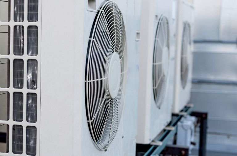 A row of mini-split air conditioner condensers on a rooftop of a building