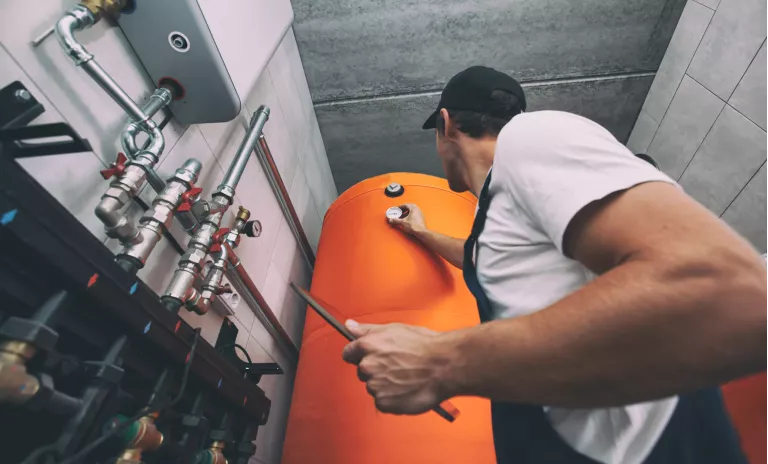 The technician checking the heating system in the boiler room with tablet in hand