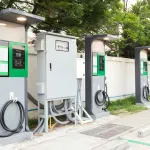 fast electric vehicle car charger with cable supply plugged and power supply box at EV station sites. EV car charging station in car park at supermarket ready to serve future automotive and city life.