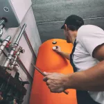 The technician checking the heating system in the boiler room with tablet in hand