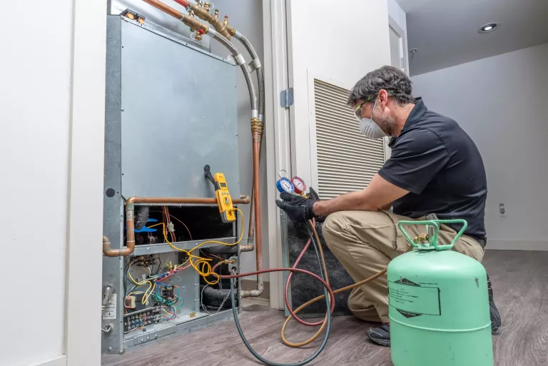 Checking refrigerant charge on a heat pump, wearing a safety mask and glasses