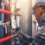 HVAC Heating Technician Making Final Check of the System. Checking All Hot Water Valves, Pipelines and Counters.