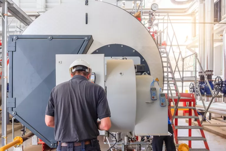 Maintenance engineer working with gas boiler of heating system equipment in a boiler room