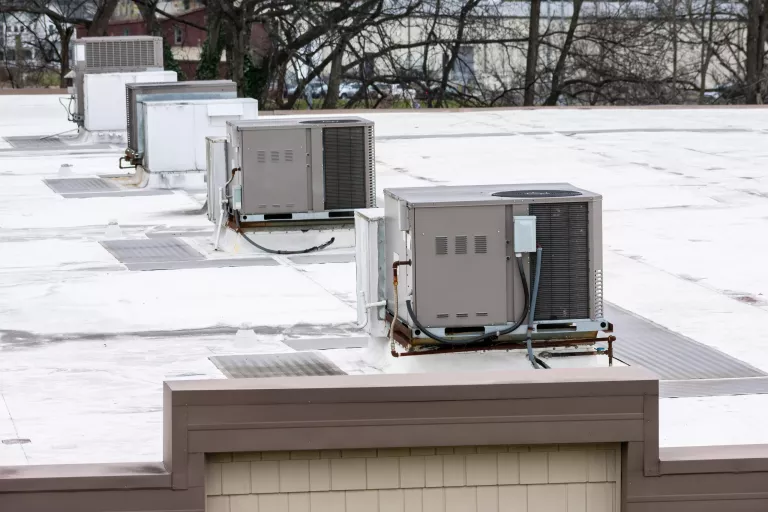 Horizontal shot of a row of rooftop air conditioning units on top of a medical office building.