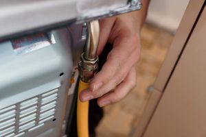Professional Technician Connecting Gas Line to Oven for Installation.