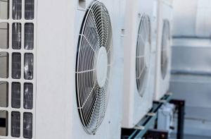 A row of mini-split air conditioner condensers on a rooftop of a building
