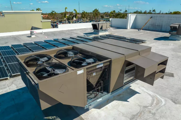 External unit of commercial air conditioning and ventilation system installed on industrial building roof. Exhaust vent on flat factory rooftop.