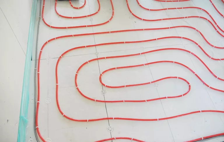 A close-up on hot water heating tubes installation of energy efficient hydronic radiant water floor heating system.