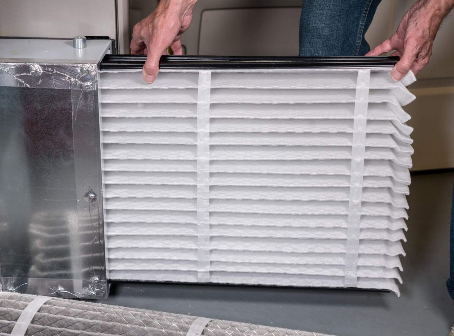 Senior caucasian man changing a folded air filter in the HVAC furnace system in basement of home