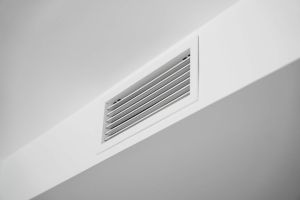 Close-up of a white ceiling ventilation grille in a modern residential interior, showcasing HVAC airflow design, minimal architecture, clean surfaces and contemporary home style.