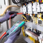 Electrician engineer tests electrical installations and wires on relay protection system. Adjustment of scheme of automation and control of electrical equipment.